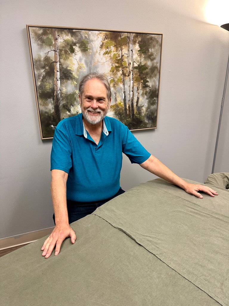 David sitting behind a massage table